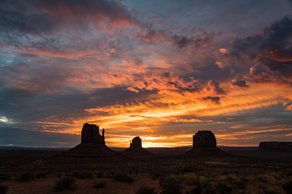 Sunset valley wallpaper with orange purple sky rugged rock silhouettes and sparse bushes landscape