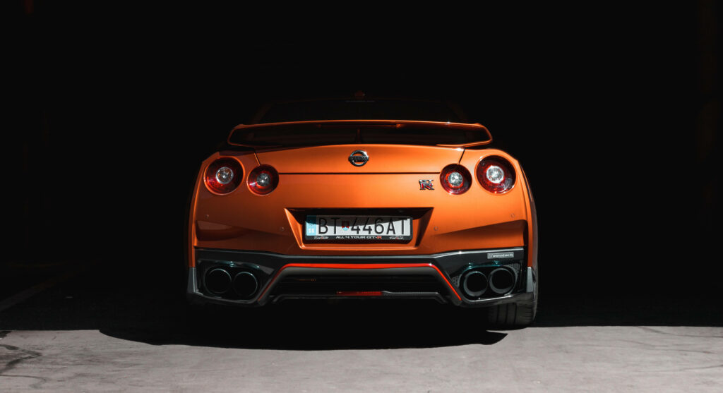 Stunning AMOLED Wallpaper: Orange Nissan SUV Rear View on Dark Background