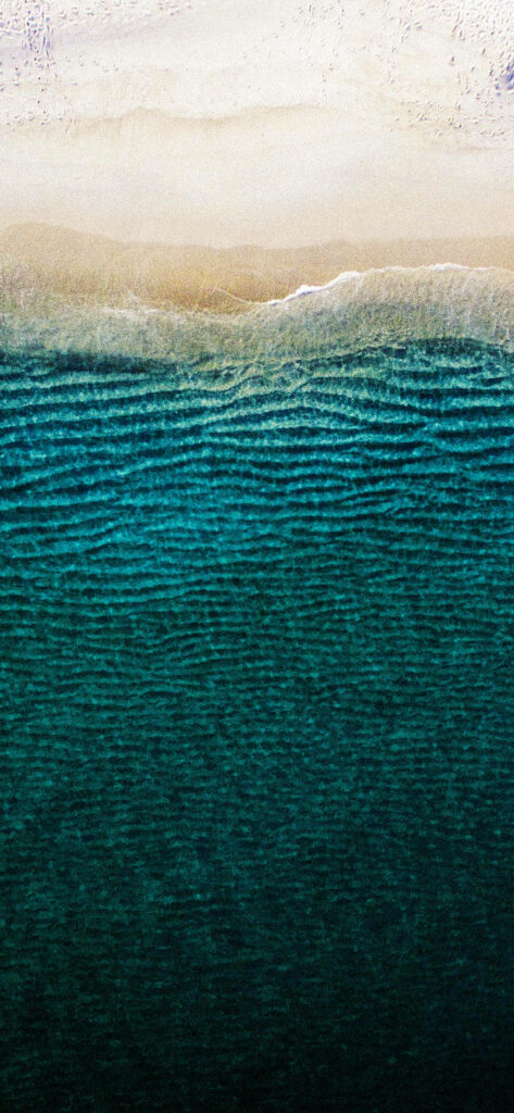 Stunning Beach Aerial: Serene Sandy Shore & Dark Teal Waves Wallpaper