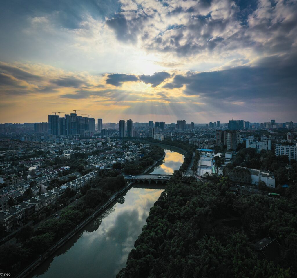 Stunning Sunset Cityscape Wallpaper: Aerial River View & Lush Greenery