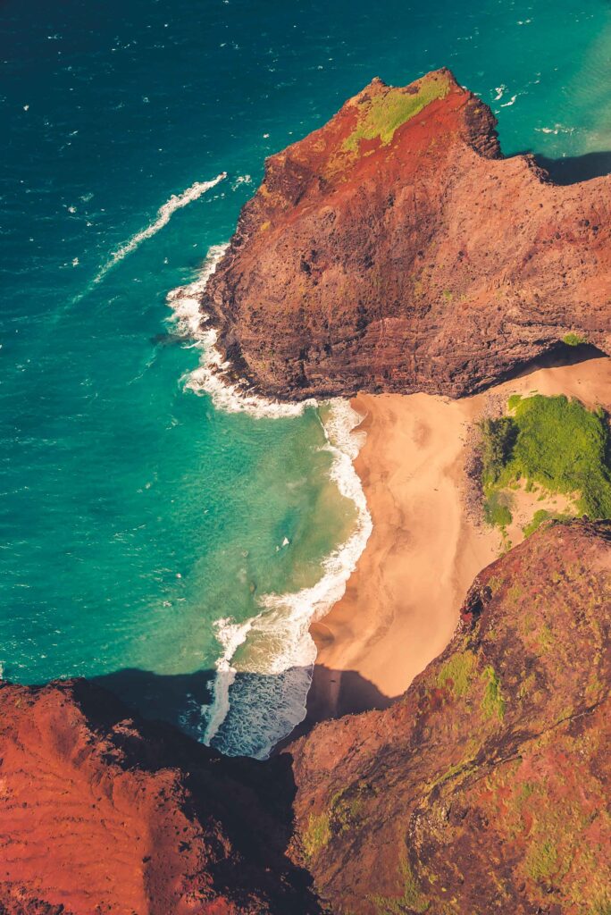 Aerial view of rugged rocky coastline with turquoise sea and sandy beach between cliffs Wallpaper