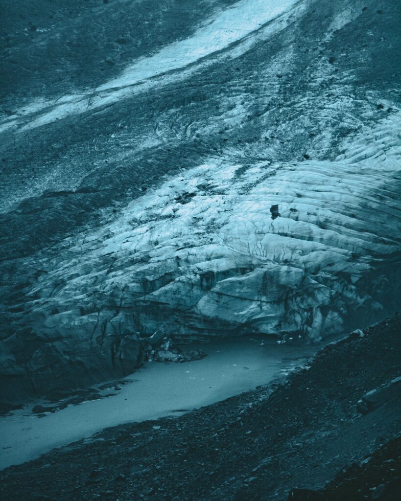 Aerial view of blue gray glacier with textured ice layers and rugged cold terrain background Wallpaper