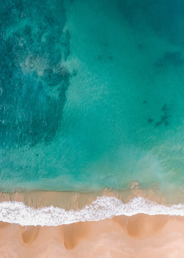 Serene Aerial View of Turquoise Shallow Sea and Sandy Shoreline Wallpaper