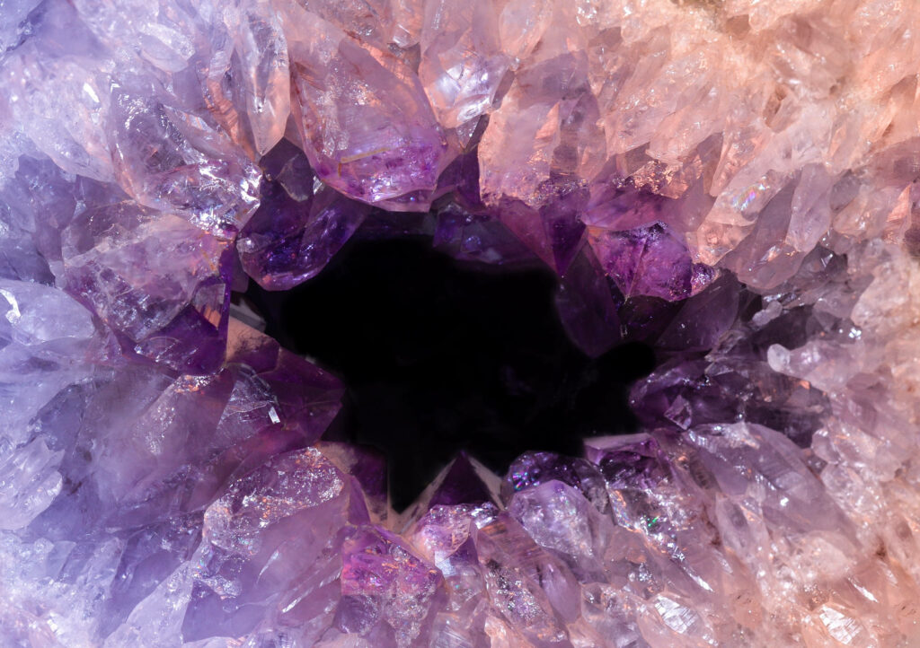 Close-up of hollow amethyst geode with vibrant purple crystals and dark empty center wallpaper background