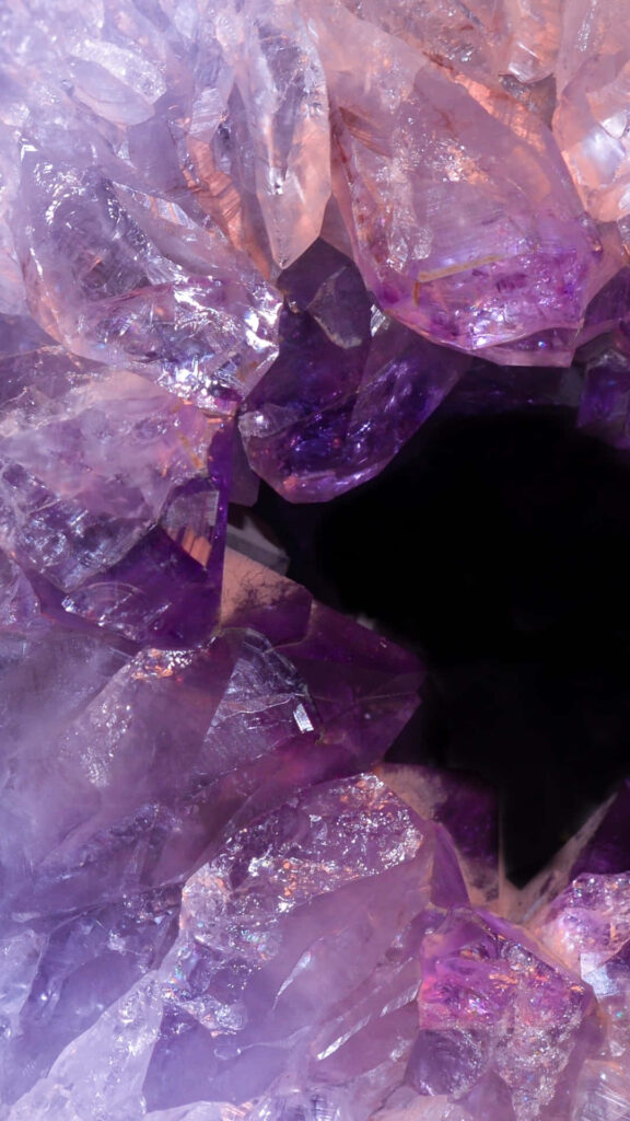 Vibrant amethyst geode wallpaper with sparkling purple crystals and deep dark center background