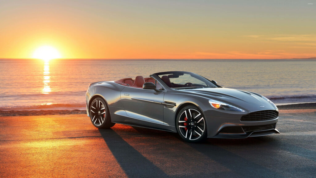 Sleek Aston Martin Vanquish Wallpaper: Sunset Ocean Background