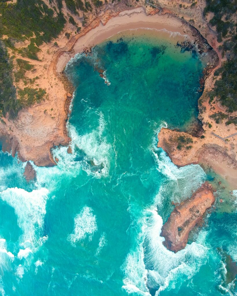 Aerial view of Australian coast with turquoise waves crashing against cliffs and sandy beach Wallpaper