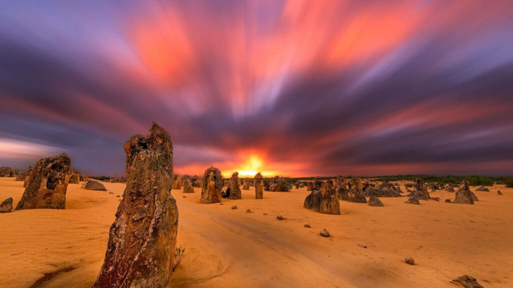 Towering rock formations under vibrant colorful aurora lights in Australian Outback sunset Wallpaper