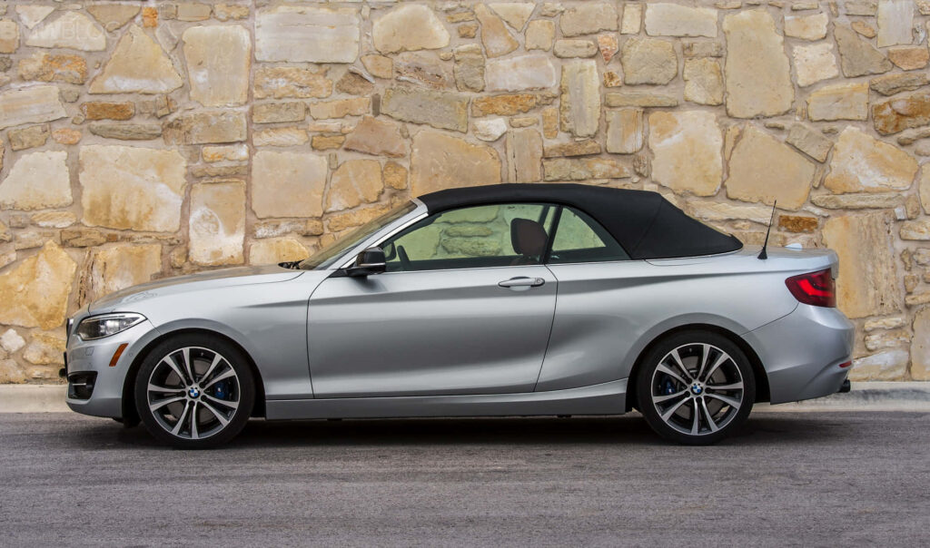 Elegant BMW 2 Series Convertible Against Rustic Stone Wall - Wallpaper