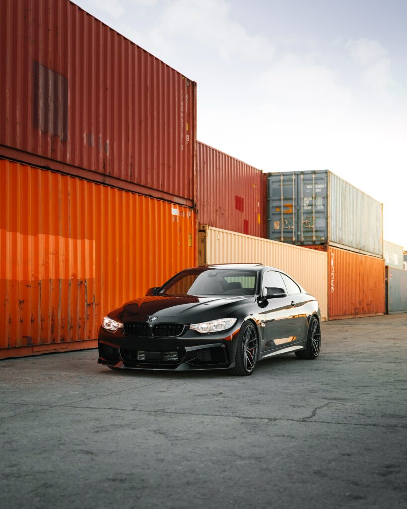 Stunning Black BMW 3 Series Amid Vibrant Shipping Containers Wallpaper