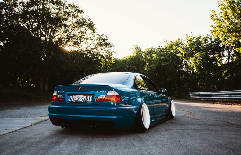 Stunning BMW M3 Rear View Wallpaper on Sunlit Road with Greenery