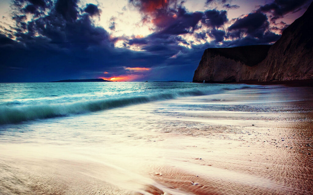 Dramatic Beach Sunset Wallpaper: Vibrant Colors & Rugged Cliffs