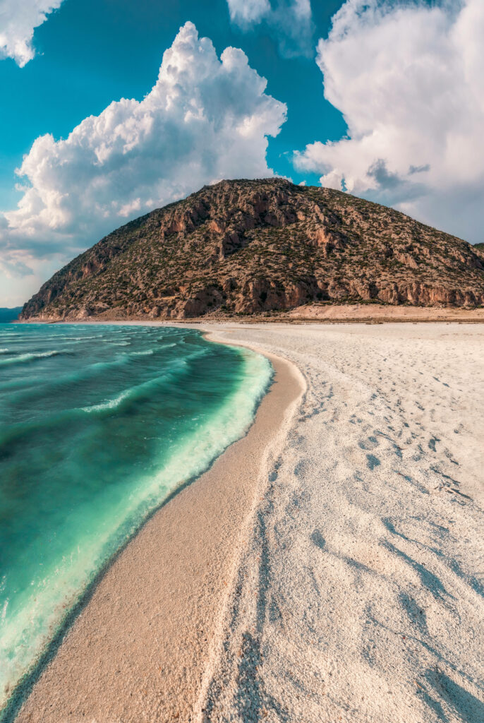 Pristine White Sand Beach with Turquoise Waters and Rugged Hillside Wallpaper