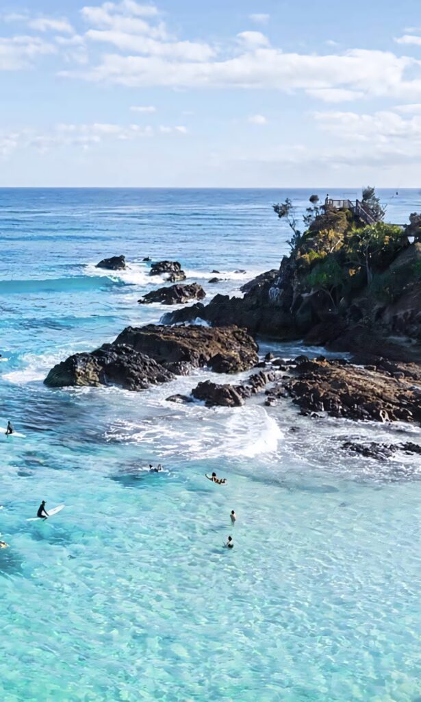 Serene Surf Beach Wallpaper: Turquoise Waters & Surfers Under Blue Sky