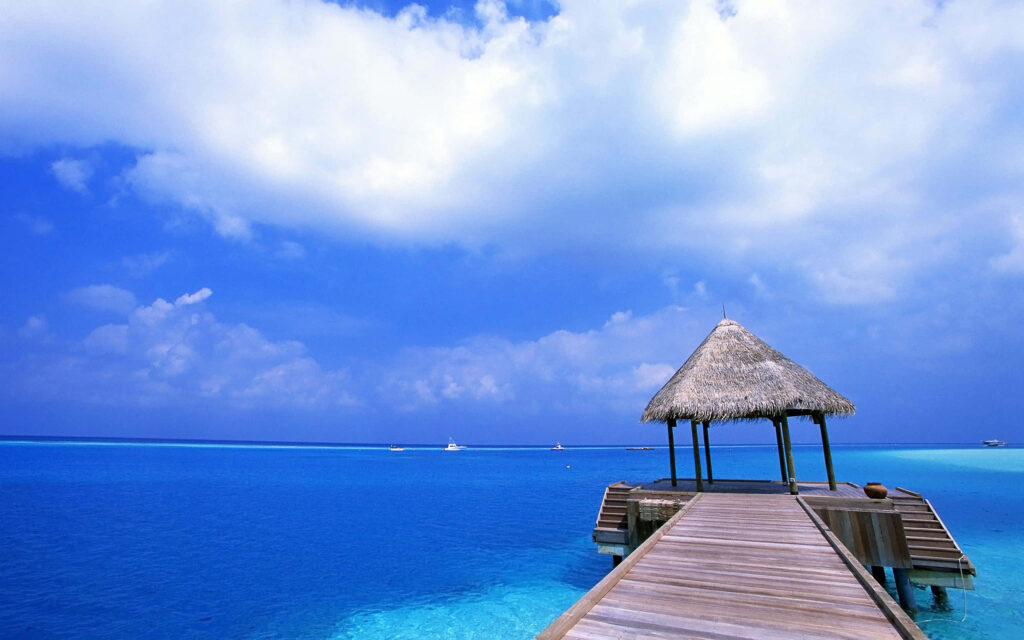 Stunning Beach Wallpaper: Thatched Hut on Pier in Turquoise Ocean