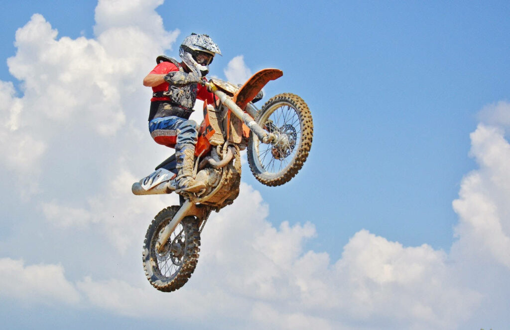 Stunning Bike Rider Stunt Wallpaper Against Blue Sky & Clouds
