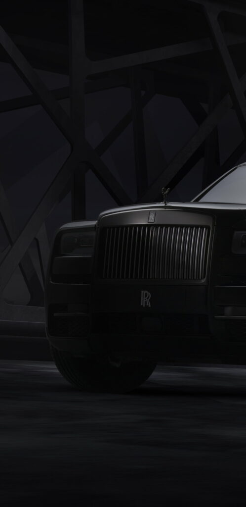 Matte black Rolls-Royce grille with Spirit of Ecstasy in moody dark architectural background wallpaper