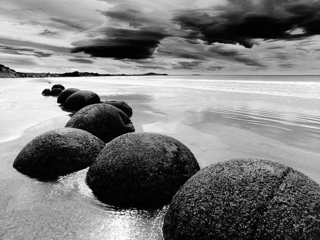 Stunning Black and White Beach Rocks with Dramatic Sky Background Wallpaper