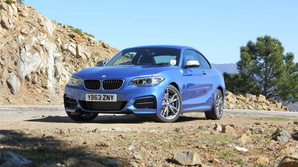 Vibrant Wallpaper of a Blue BMW 2 Series on Scenic Road