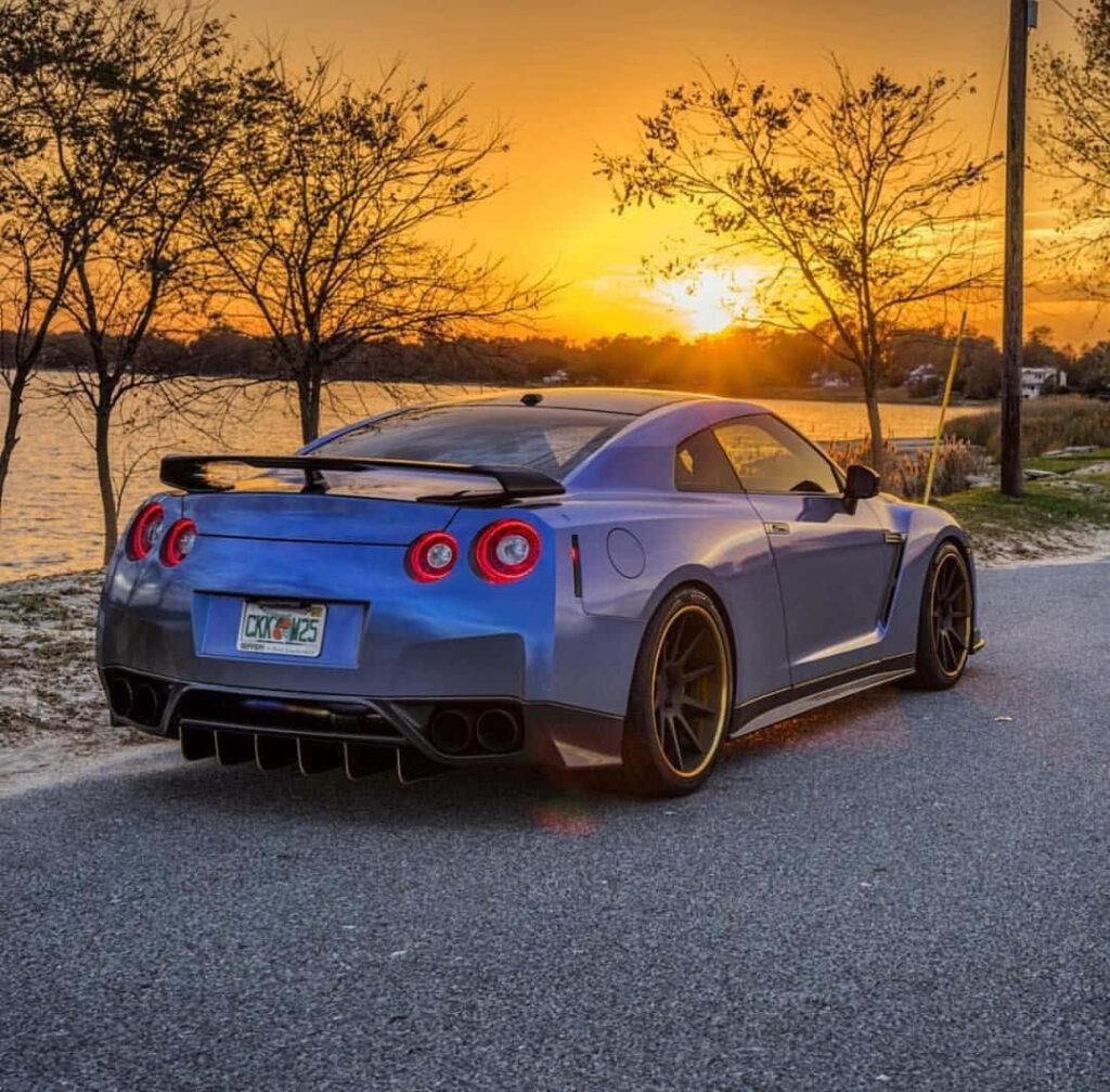 Blue Nissan R35 GTR parked lakeside at sunset with vibrant sky scenic wallpaper background