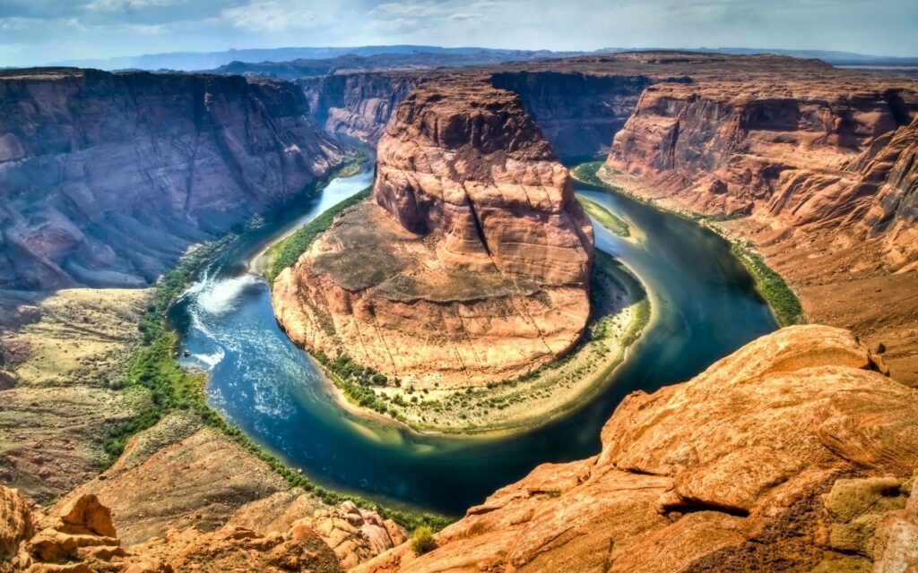 Vast canyon with rugged cliffs and winding blue river in horseshoe bend vibrant natural landscape Wallpaper