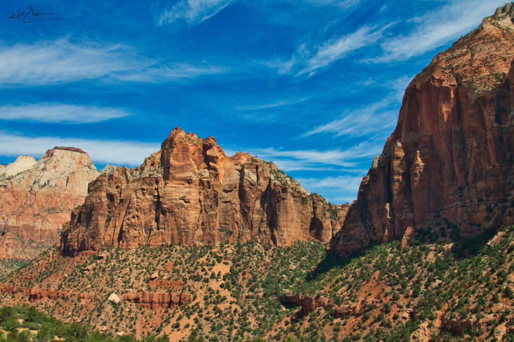 Stunning canyon landscape with red rock formations green vegetation and vivid blue sky wallpaper