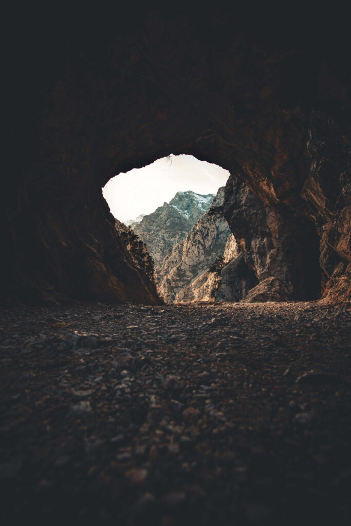 Stunning Natural Cave Entrance with Rugged Mountains: Nature's Beauty Wallpaper
