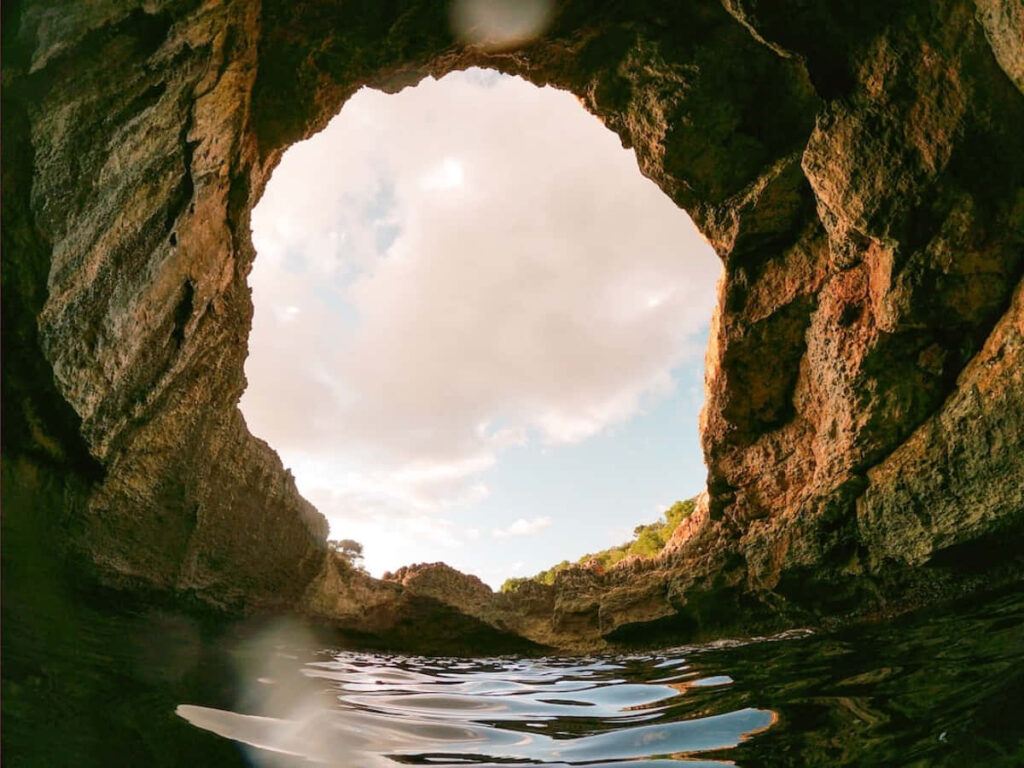 Breathtaking Cave View Wallpaper: Serene Sky & Fluffy Clouds