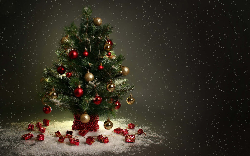 Illuminated Christmas Tree with Red & Gold Ornaments in Snowy Scene Wallpaper