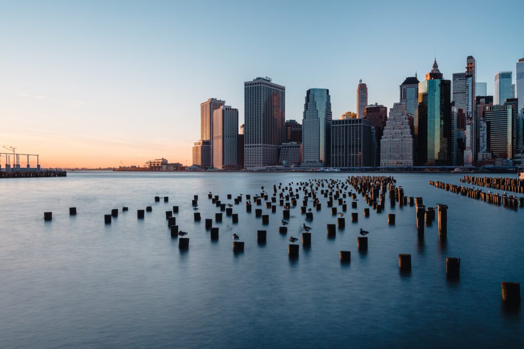 Stunning Sunset Cityscape: Towering Skyline & Serene Waters Wallpaper
