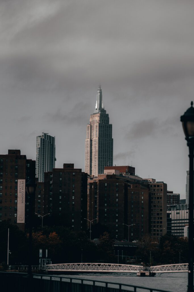 Stunning Cityscape Wallpaper: Skyscraper & Bridge Under Cloudy Sky