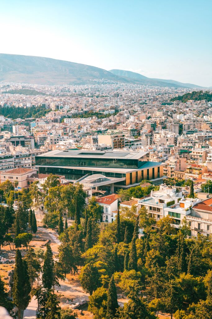 Stunning Cityscape Wallpaper: Rooftops, Trees & Majestic Mountains