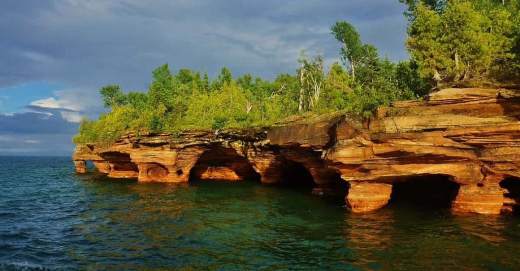 Sunlit Cliffside Oasis Overlooking Tranquil Waters - A Serene View Wallpaper