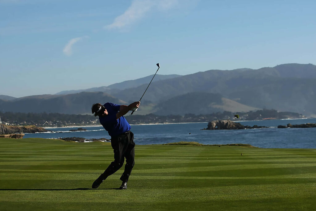 Golfer's Powerful Swing on Lush Coastal Course with Blue Sky Wallpaper