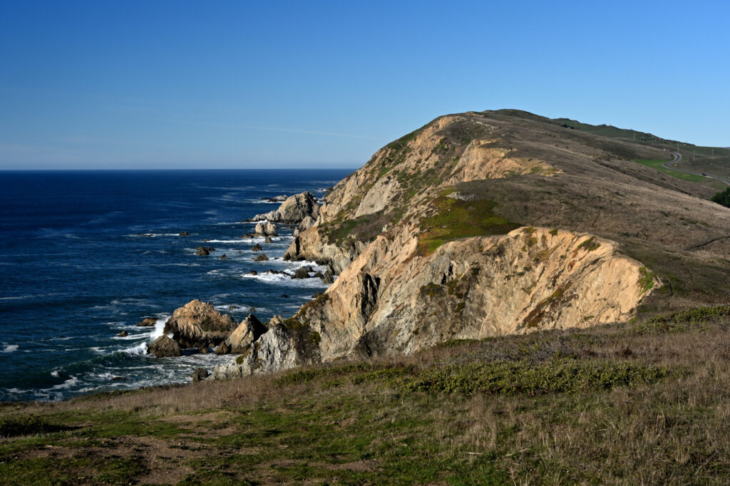 Coastal landscape with rugged rocks steep hills deep blue sea and clear sky wallpaper background