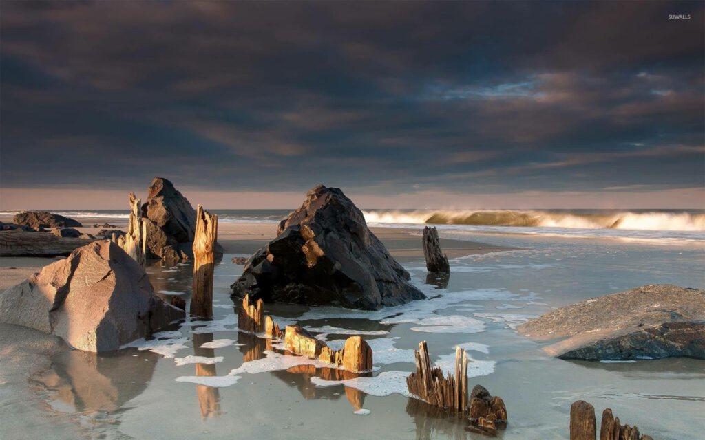 Dramatic Beach Wallpaper: Rock Formations & Moody Sky Background