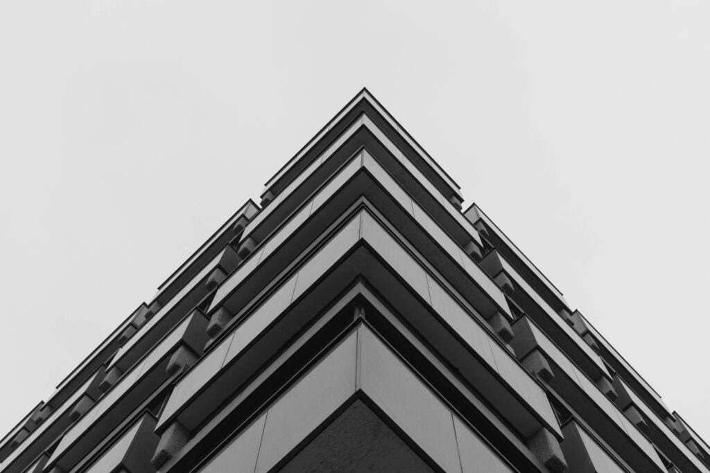 Sharp Contrast: Striking Concrete Skyscraper Piercing a Clean White Canvas Wallpaper