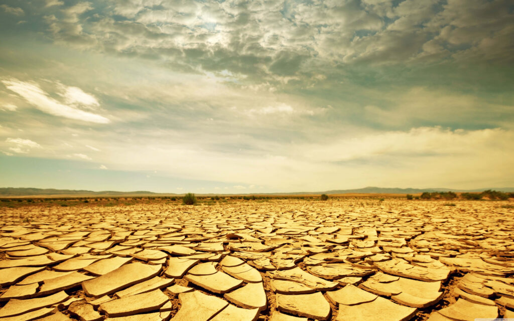 Barren Desert Wallpaper: Cracked Landscape & Dramatic Golden Sky