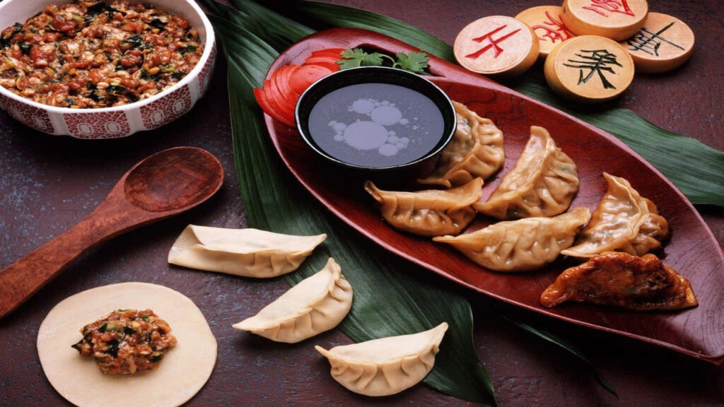 Delicious Dumplings with Dipping Sauce on Leafy Wallpaper Background