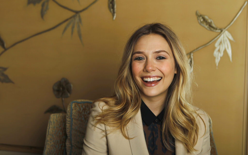 Elegant Elizabeth Olsen Wallpaper: Radiant Smile on Golden Background