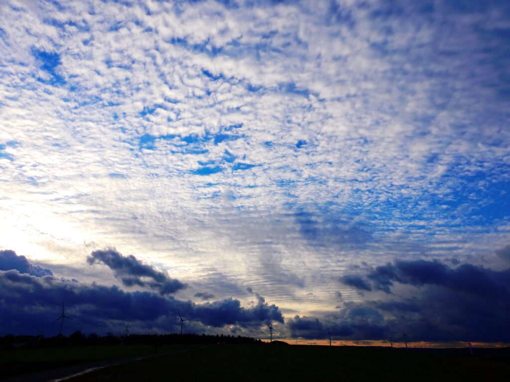 Evening sky wallpaper with textured clouds deep blue tones and soft sunset light over horizon