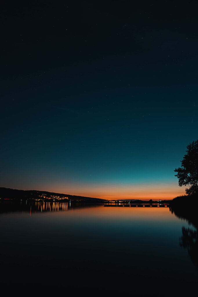 Serene Evening Wallpaper: Buildings Reflecting on Calm Lake
