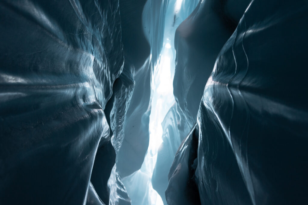 Ice canyon wallpaper with deep blue glacier walls and light streaming through narrow crevice