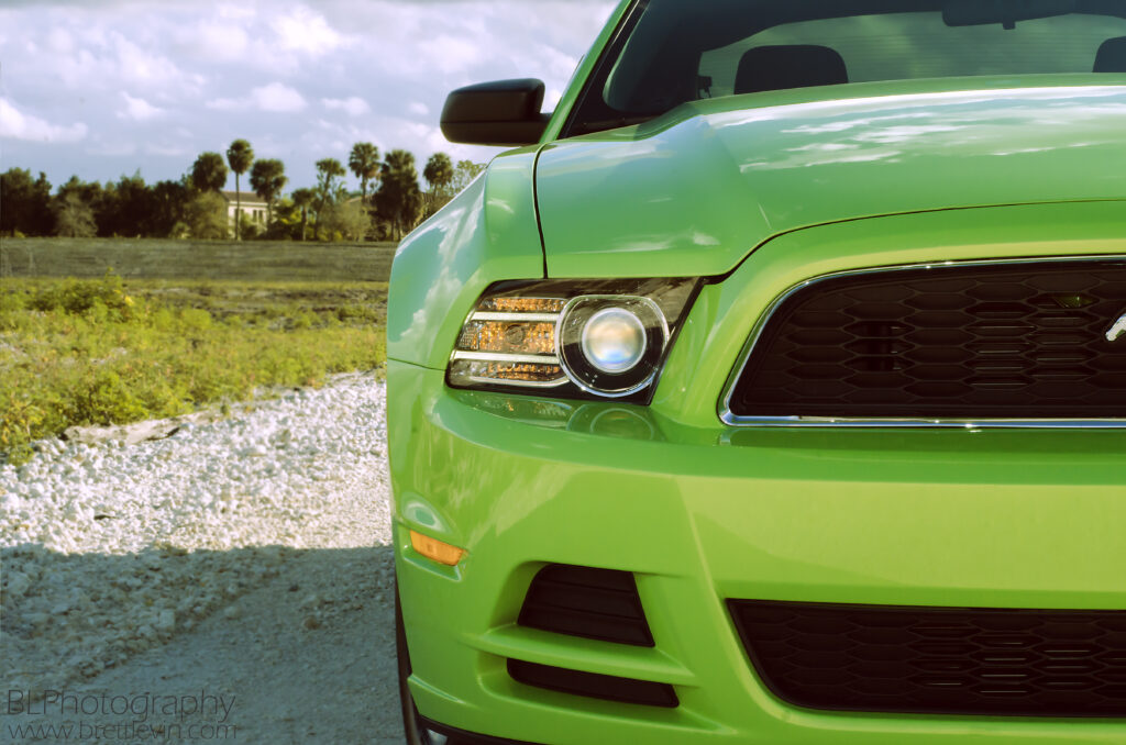 Striking Green Ford Mustang: Front View in Scenic Background Wallpaper