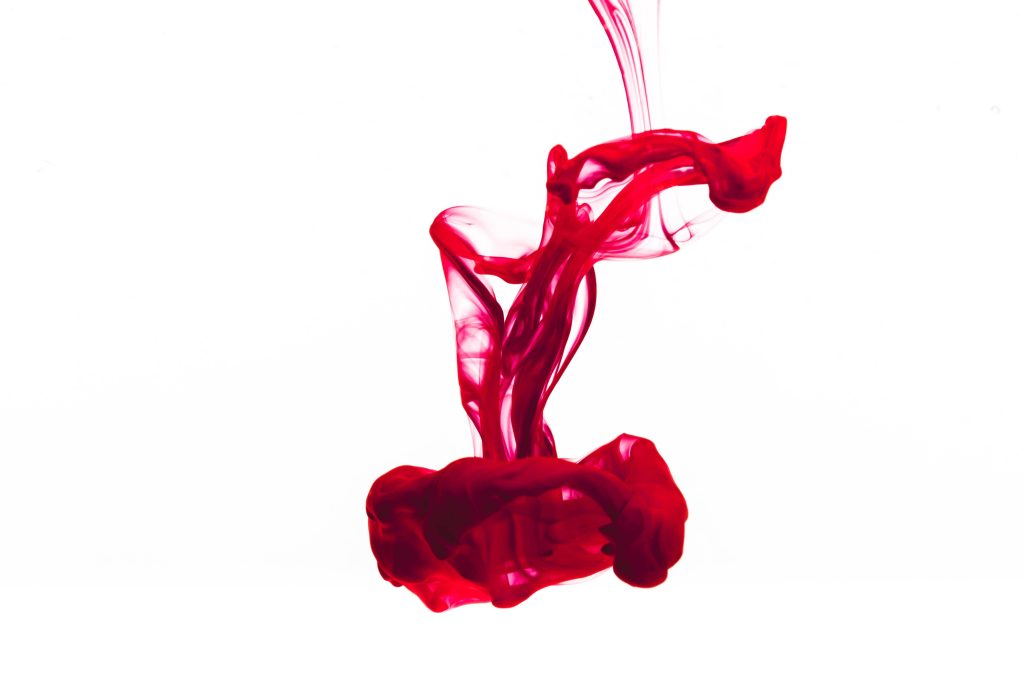 HD red ink swirling in water abstract wallpaper with fluid crimson pigment on white background