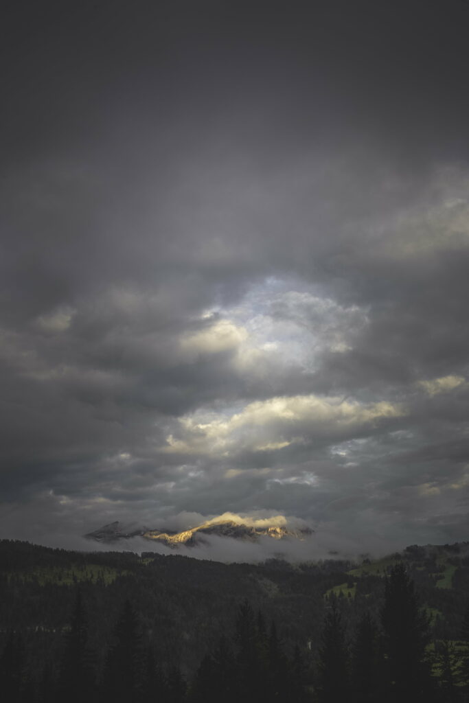 Serene Mountain Landscape: Moody Clouds and Sunlit Peaks - HD Wallpaper