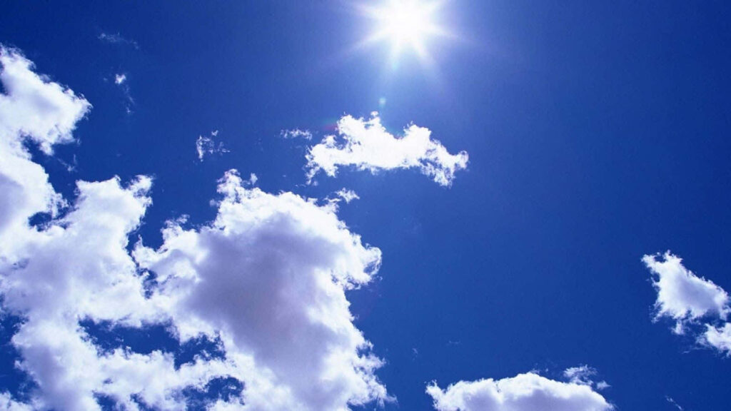 Stunning Blue Sky Wallpaper with Fluffy Clouds and Radiant Sun