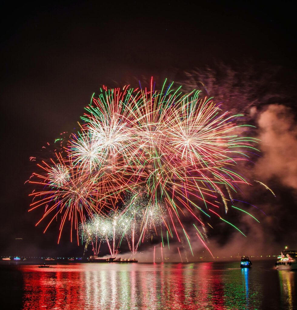 Vibrant Fireworks Over Calm Water: Stunning Night Wallpaper