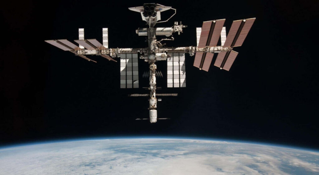Stunning Wallpaper: ISS Orbiting Earth with Solar Panels in Space
