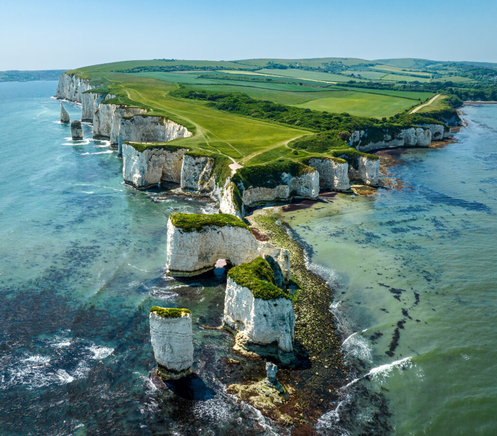 Vibrant island landscape with white cliffs green trees blue sea and clear sky wallpaper background